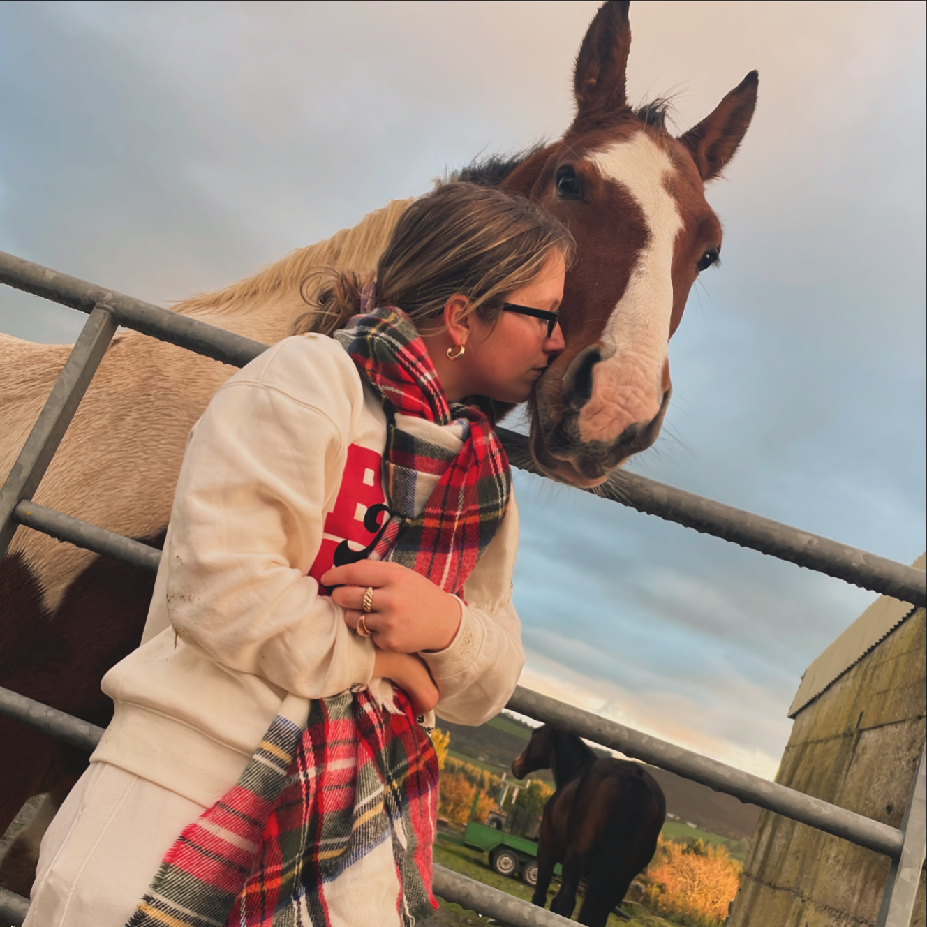 Amy resting her forehead against a horse at golden hour